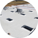 A white rooftop adorned with multiple square skylights and an HVAC unit showcases expert craftsmanship in residential roofing services. The flat expanse blends seamlessly with the grassy and tree-lined backdrop, adding serene beauty to function.